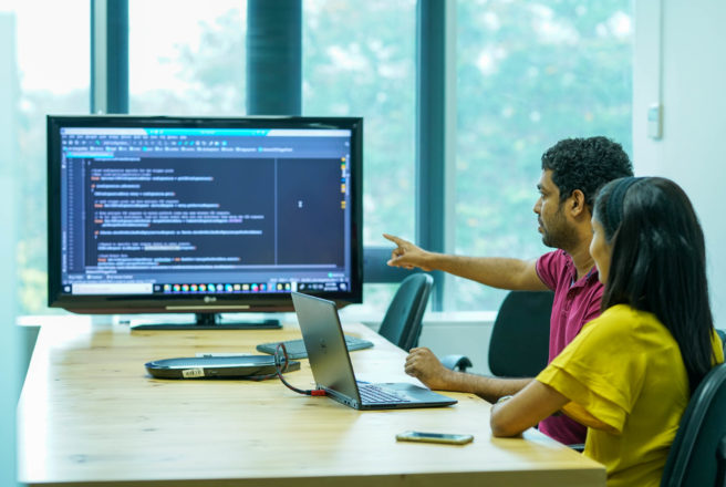 Two Cambio staff discussing software that is displayed on a monitor